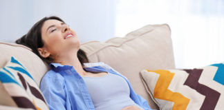 Jak radzić sobie ze wzdęciami? Kobieta ubrana na niebiesko cierpiąca z powodu wzdęć brzucha