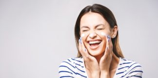 Jak pielęgnować skórę wokół oczu? uśmiechnięta kobieta z kremem pod oczami