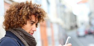 Jakie smartfony będą królować tej zimy? chłopak z lokami na głowie wpatrzony w smartfon