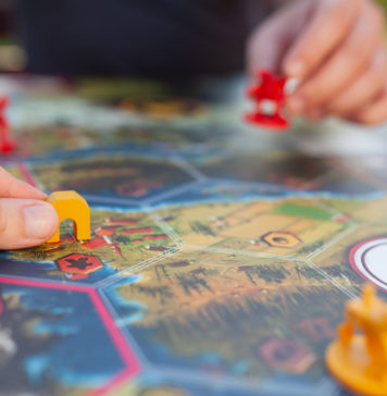 Jak nie nudzić się w podróży? Zagrajmy w planszówki! dwie osoby grające w planszówkę w podróży