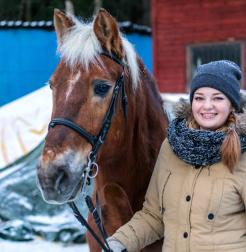 Zimowy ubiór do stajni – co założyć, aby nie zmarznąć? uśmiechnięta dziewczyna z koniem zimą