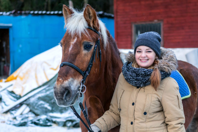 uśmiechnięta dziewczyna z koniem zimą
