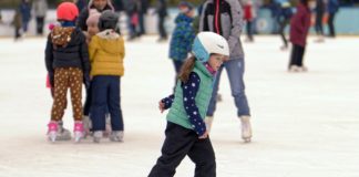 Ferie zimowe w mieście? Jak najbardziej! Dziewczynka jeżdżąca na łyżwach w kasku na lodowisku