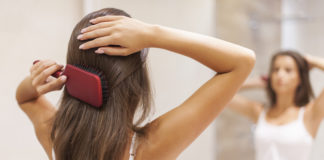 Wypadanie włosów?! Powiedz STOP! Kobieta przed lustrem czesząca włosy szczotką