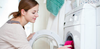 Pranie kurtki puchowej w pralce – czy to dobry pomysł? Kobieta robiąca pranie w pralce automatycznej