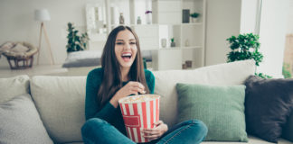 Jakie seriale zagraniczne królowały w Polsce w latach 90? dziewczyna z popcornem oglądająca kultowy serial