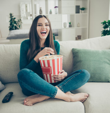 Jakie seriale zagraniczne królowały w Polsce w latach 90? dziewczyna z popcornem oglądająca kultowy serial