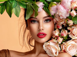 kobieta w pięknym makijażu z kwiatami przy twarzy