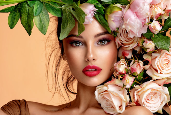 kobieta w pięknym makijażu z kwiatami przy twarzy