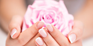 Co zrobić, aby mieć zawsze piękne dłonie? kobieta z zadbanymi paznokciami i dłońmi trzymająca różę w dłoniach