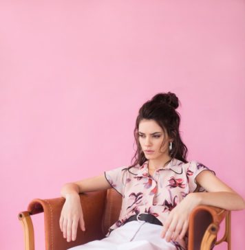 5 modnych stylizacji dla wysokich kobiet wysoka modna kobieta siedząca na krześle na różowym tle