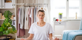 Joga i medytacja – skąd ich popularność podczas pandemii? Młoda dziewczyna medytująca w domu na macie