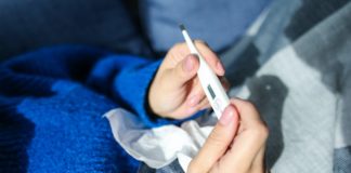 Sposoby na obniżenie temperatury w domowych warunkach kobieta trzymająca w ręku termometr