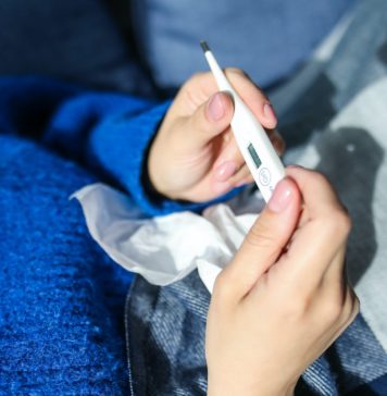 Sposoby na obniżenie temperatury w domowych warunkach kobieta trzymająca w ręku termometr