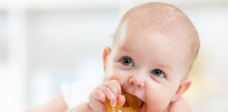 Objawy ząbkowania u dzieci ząbkujące niemowlę z gryzakiem w buzi