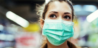 Szybko i mądrze, czyli o robieniu zakupów w czasie epidemii dziewczyna w maseczce na twarzy na tle supermarketu