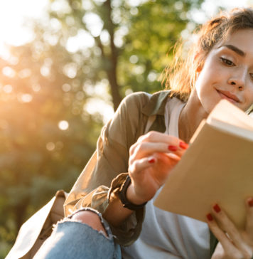 10 wciągających książek, idealnych na długie dni i wieczory młoda dziewczyna czytająca książkę na zewnątrz