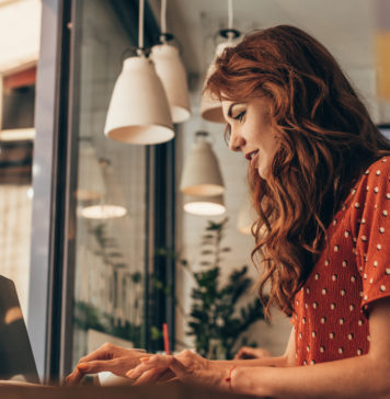 Myślisz o prowadzeniu własnego bloga? Te wskazówki pomogą Ci w tym rudowłosa dziewczyna przy laptopie pisząca na blogu