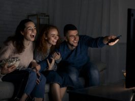 rozbawieni młodzi ludzie przed telewizorem
