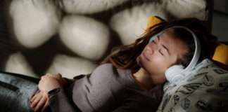 Nauka języka przez sen – czy to możliwe? młoda kobieta śpiąca w słuchawkach na uszach