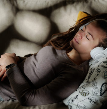 Nauka języka przez sen – czy to możliwe? młoda kobieta śpiąca w słuchawkach na uszach