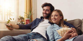 Uwielbiasz seriale komediowe? Tych produkcji po prostu nie możesz nie znać! para oglądająca serial na kanapie w domu