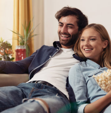 Uwielbiasz seriale komediowe? Tych produkcji po prostu nie możesz nie znać! para oglądająca serial na kanapie w domu