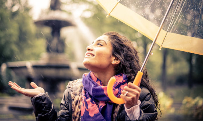 szczęśliwa kobieta pod parasolem w czasie deszczu