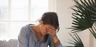 Czym jest nerwica natręctw? W jaki sposób się objawia? Jak się jej przeciwstawić? smutna kobieta siedząca na kanapie