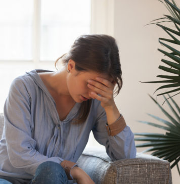 Czym jest nerwica natręctw? W jaki sposób się objawia? Jak się jej przeciwstawić? smutna kobieta siedząca na kanapie