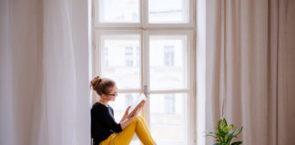 Najciekawsze kryminały na jesień młoda kobieta czytająca w oknie