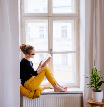 Najciekawsze kryminały na jesień młoda kobieta czytająca w oknie