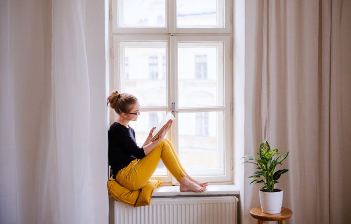 młoda kobieta czytająca w oknie