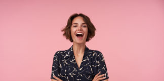 Sukienki dla niskich kobiet – jaki krój wybrać? kobieta w czarno białej sukience na różowym tle