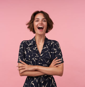 Sukienki dla niskich kobiet – jaki krój wybrać? kobieta w czarno białej sukience na różowym tle