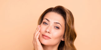 Laserowe usuwanie blizn i zmarszczek zbliżenie na kobietę dotykająca twarzy na pomarańczowym tle