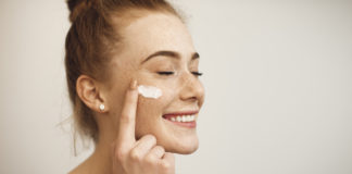 Czego nie może zabraknąć w damskiej kosmetyczce? kobieta z kremem na twarzy