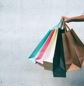 Zakupoholizm – skąd się bierze, jakie ma objawy i co zrobić, aby mu przeciwdziałać? zbliżenie na rękę trzymającą torby na zakupy