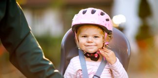 Pierwszy fotelik rowerowy – na co zwrócić uwagę przy zakupie? dziewczynka w foteliku rowerowym