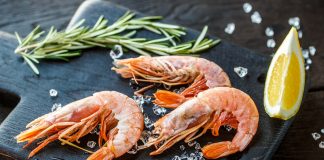 Najczęstsze błędy podczas przyrządzania owoców morza. Jak ich uniknąć i nadać potrawom wyśmienity smak? świeże krewetki na lodzie na desce