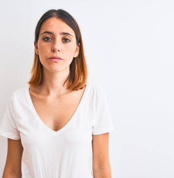 Intensywniejsze owłosienie na twarzy u kobiet – skąd się bierze ten problem i jak się z nim uporać? smutna kobieta patrząca w obiektyw