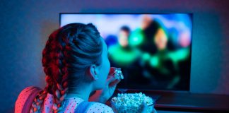 Netflix na wakacje – co warto obejrzeć? dziewczyna z popcornem oglądająca telewizję
