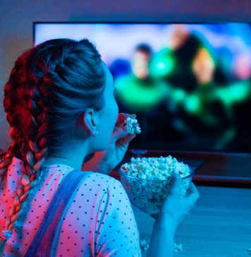 Netflix na wakacje – co warto obejrzeć? dziewczyna z popcornem oglądająca telewizję