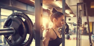 Jak ćwiczyć na siłowni? Przykładowe ćwiczenia! dziewczyna podnosząca ciężary
