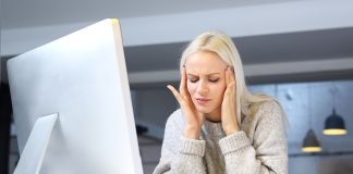 Migrena z aurą – co może pomóc? Migrenowy ból głowy. Zmęczona kobieta pracuje przy komputerze